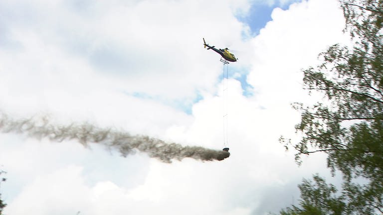 Hubschrauber fliegt über Waldgebiet und verteilt Kalk (Foto: SWR)