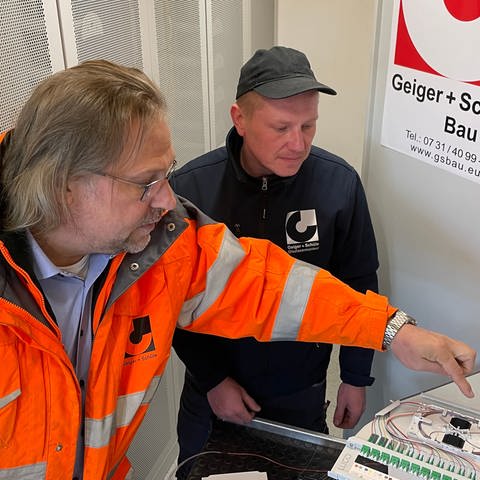 Rolf Mezger, Geschäftsführer von Geiger + Schüle Bau (links), im Gespräch mit Glasfasermonteur Valerii Saramotin. An der Baustelle in der Zeitblomstraße werden Glasfaserleitungen verlegt.