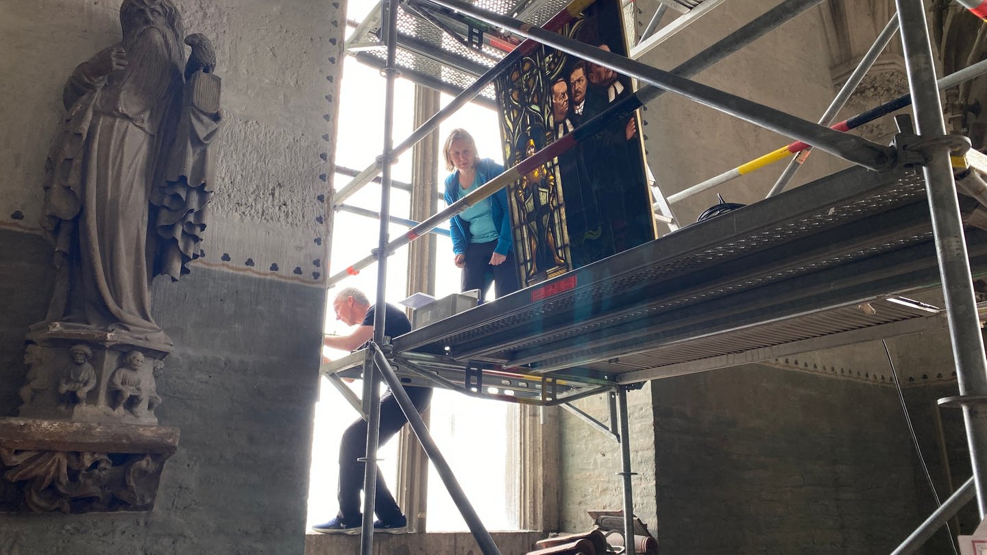 Die Restauratoren stehen auf einem Gerüst im Ulmer Münster und arbeiten an der Aufhängung für die Bleiglasfenster in der Christuskammer. (Foto: SWR, Maja Nötzel)
