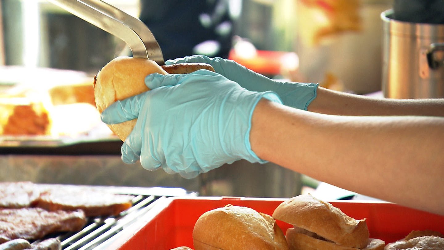Hygieneschulung für Pfingstfest in Oberkochen: Zwei Hände in Einweghandschuhen mit einer Wurst in einem Brötchen. (Foto: SWR, Frank Polifke)