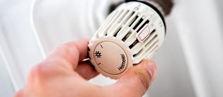 Ein Mann dreht in einer Wohnung am Thermostat einer Heizung. (Foto: dpa Bildfunk, picture alliance/dpa | Hauke-Christian Dittrich)