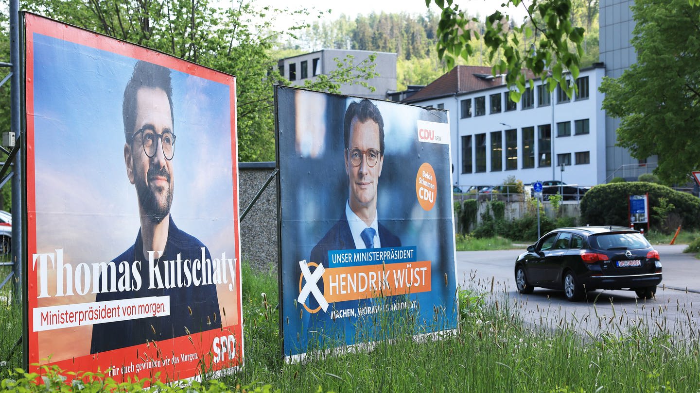 Wahlplakate mit Portraits der Spitzenkandidaten von CDU, Ministerpräsident Hendrik Wüst (r) und SPD, Thomas Kutschaty (l), stehen auf einer Wiese. Am Sonntag, den 15. Mai findet in Nordrhein-Westfalen die Landtagswahl statt.