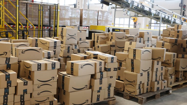 Amazon Versandkartons stapeln sich bei einem Probebetrieb in einer Logistikhalle. (Foto: dpa Bildfunk, picture alliance/dpa/dpa-Zentralbild | Bodo Schackow)