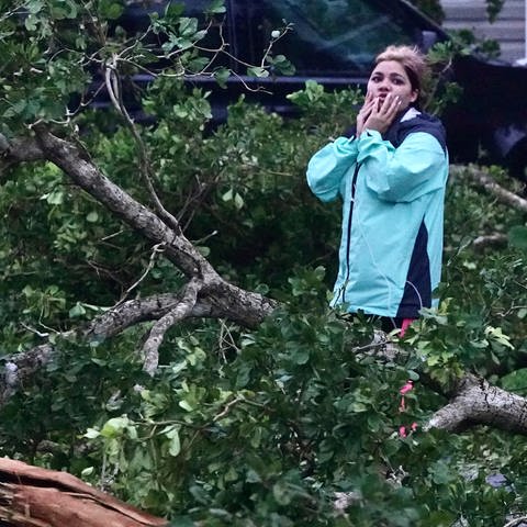 Eine Frau steht in der Einfahrt ihres Hauses in Florida und eist schockiert über die Schäden (Foto: dpa Bildfunk, picture alliance/dpa/South Florida Sun-Sentinel | Joe Cavaretta)