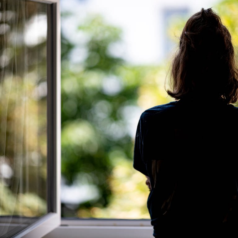 Silhouette einer Frau vor einem geöffneten Fenster. (Foto: dpa Bildfunk, picture alliance/dpa | Fabian Sommer)