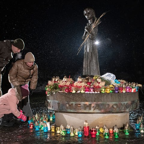 Menschen legen Blumen am Holodomor-Denkmal ab (Foto: dpa Bildfunk, picture alliance/dpa/AP | Andrew Kravchenko)