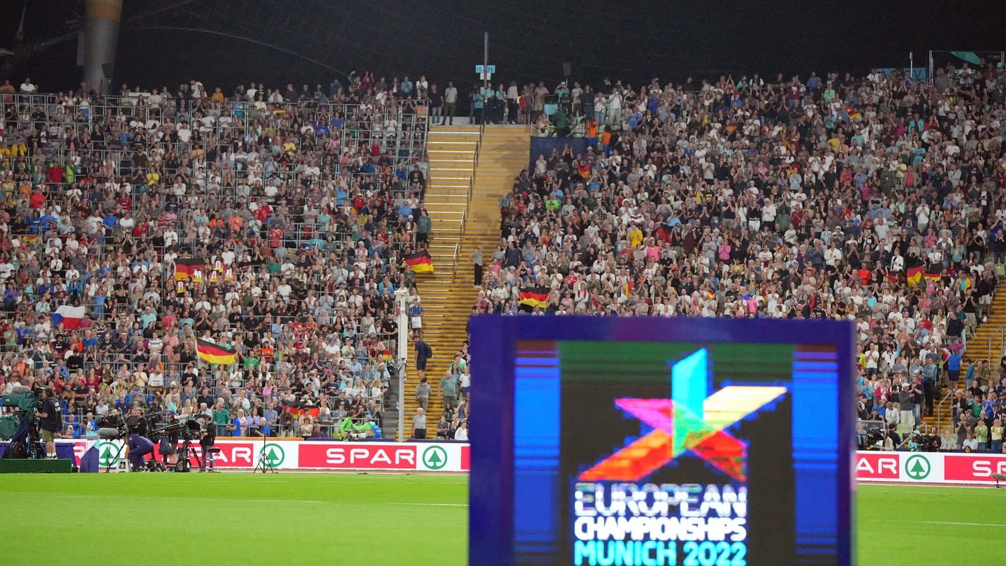 Das Logo der Leichtathletik-EM ist vor der Zuschauerkulisse in einem vollen Stadion auf einem Display zu sehen. (Foto: dpa Bildfunk, picture alliance/dpa | Soeren Stache)