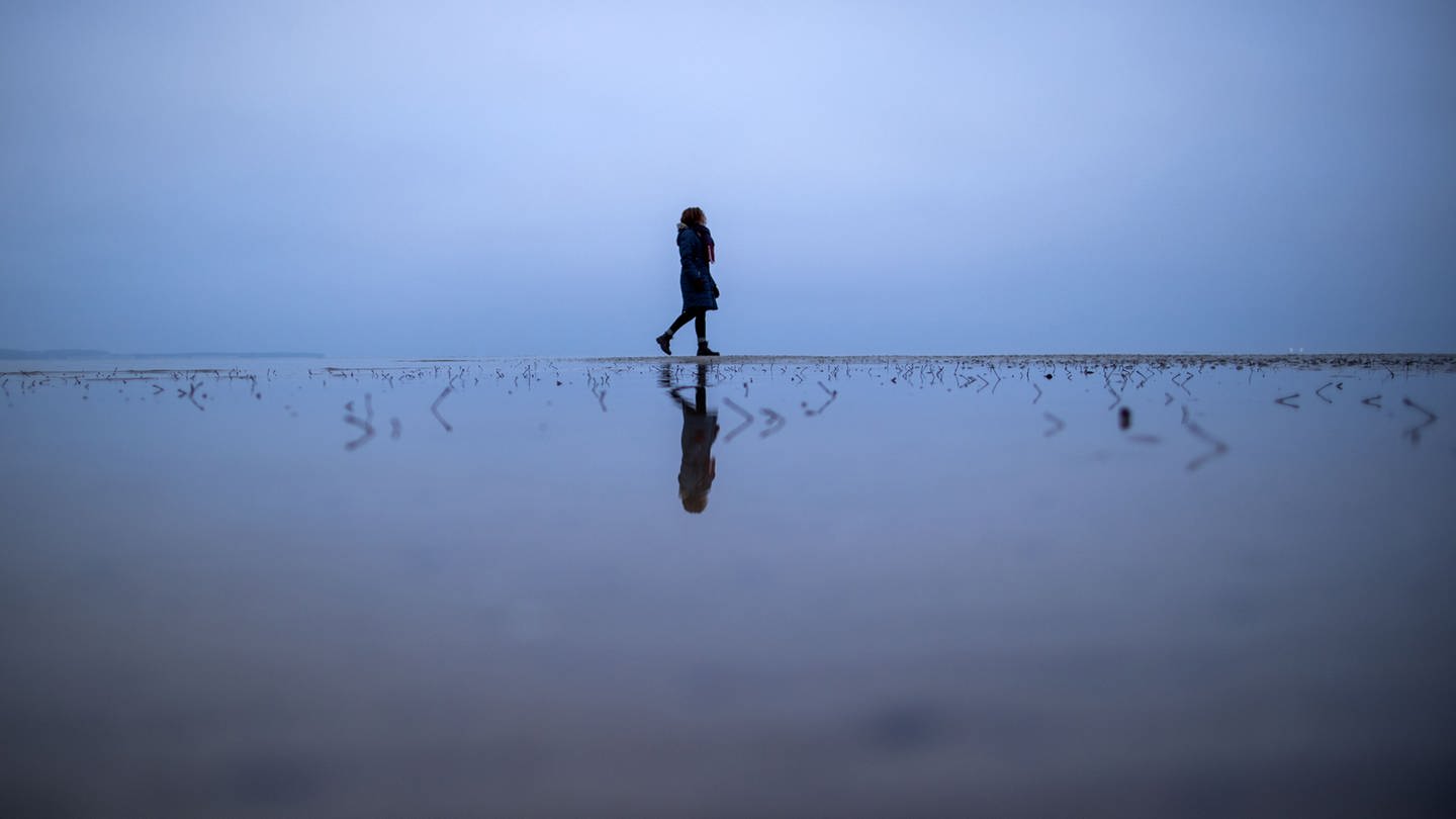 Eine Frau läuft am Meer entlang (Foto: dpa Bildfunk, picture alliance/dpa/dpa-Zentralbild | Jens Büttner)