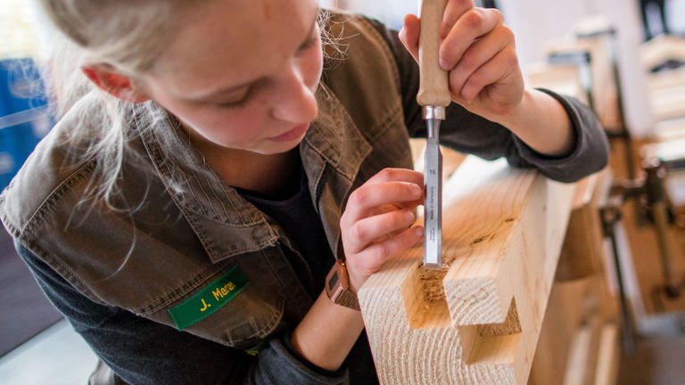 Eine Tischlerin bearbeitet einen Holzbalken (Foto: dpa Bildfunk, picture alliance / dpa | Jens Büttner)