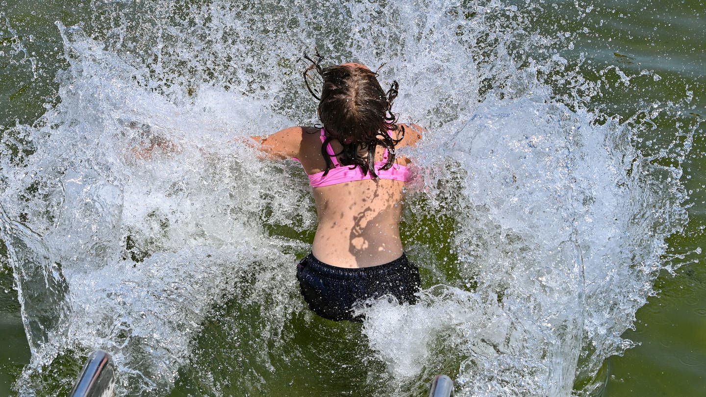 Eine junge Frau springt in einen See und das Wasser spritzt bei ihrem Aufprall zur Seite. (Foto: dpa Bildfunk, picture alliance/dpa | Patrick Pleul)