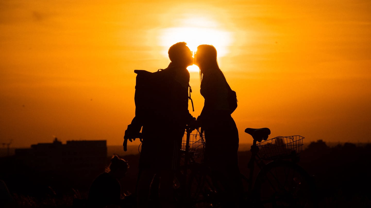 Im Licht der untergehenden Sonne küssen sich eine Frau und ein Mann auf dem Drachenberg. (Foto: dpa Bildfunk, picture alliance/ dpa/ Paul Zinken)
