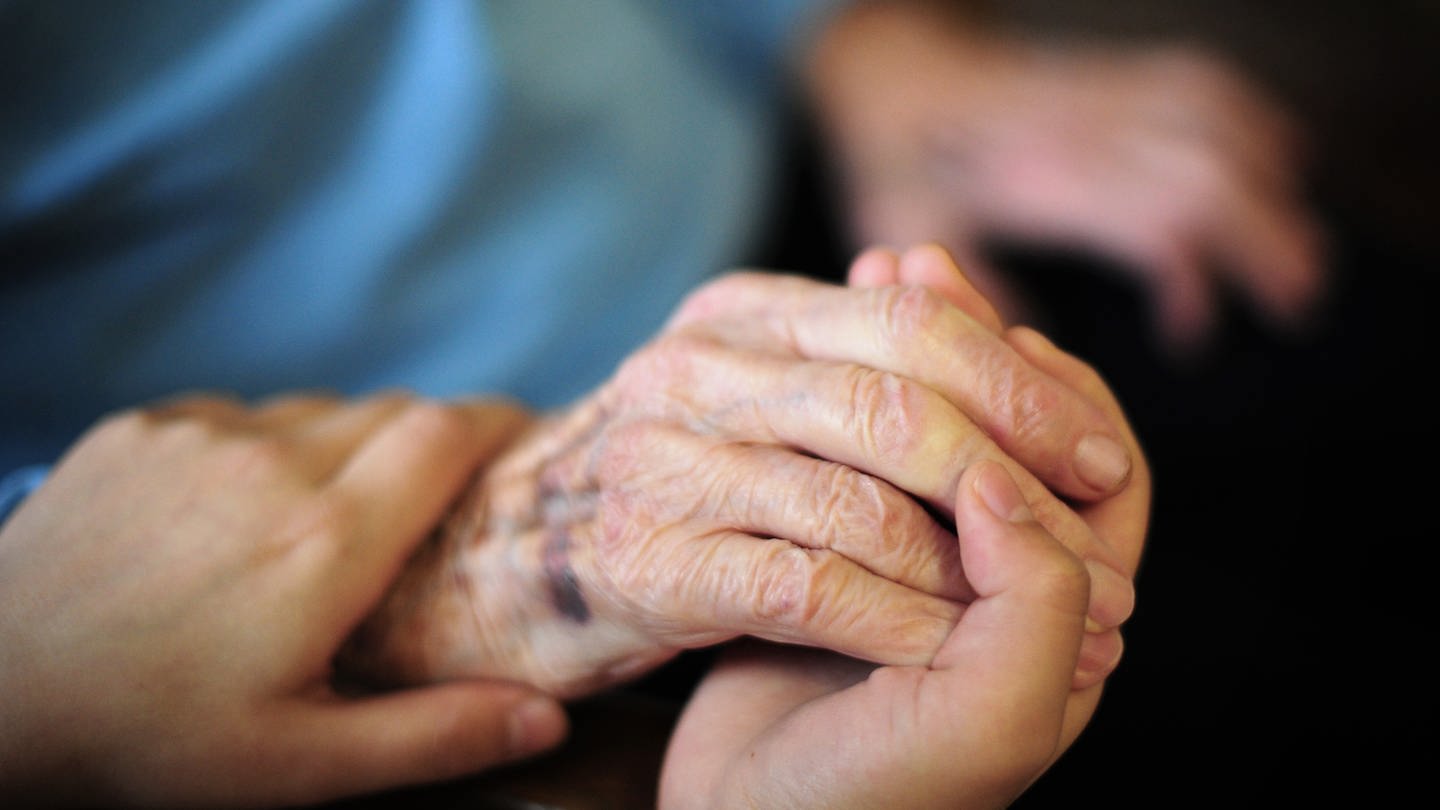 Die Hand einer alten Frau wird in einem Seniorenheim gehalten. (Foto: dpa Bildfunk, picture alliance/dpa | Daniel Reinhardt)