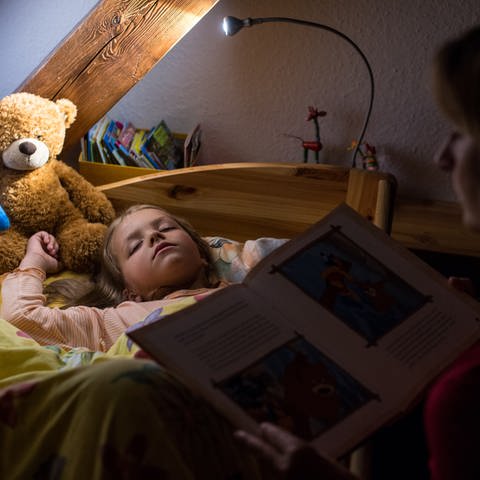 Ein fünfjähriges Mädchen ist beim Vorlesen einer Gute-Nacht-Geschichte eingeschlafen. (Foto: dpa Bildfunk, picture alliance / dpa | Patrick Pleul)