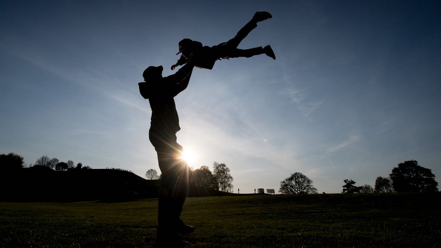 Ein Vater wirft sein Kind in die Luft (Foto: dpa Bildfunk, picture alliance / Tobias Hase/dpa | Tobias Hase)