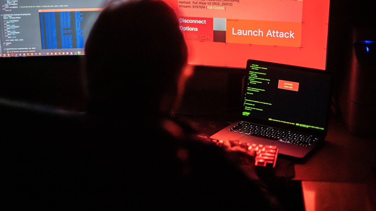 Ein Mann sitzt vor Bildschirmen, die Hacker-Programme und eine fiktive Fernlösch-Software zeigen. (Foto: dpa Bildfunk, picture alliance/dpa | Lino Mirgeler)