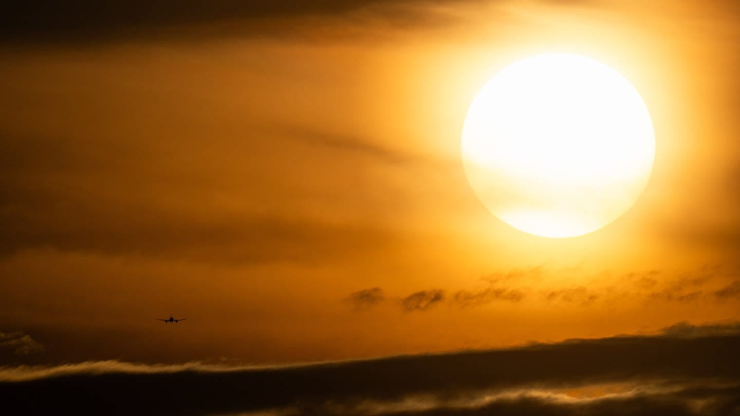 Eine Passagiermaschine durchfliegt im Landeanflug auf den Flughafen Frankfurt ein Wolkenband nahe der untergehenden Sonne. (Foto: dpa Bildfunk, picture alliance/dpa | Boris Roessler)
