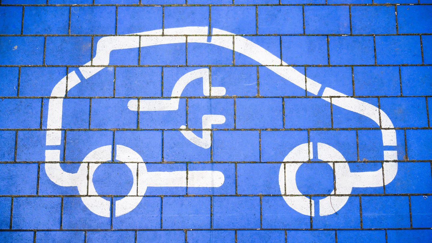 Ein blaues Symbol mit einer Steckdose für ein Auto steht für Batterietechnik im Automobilbereich (Foto: dpa Bildfunk, picture alliance/dpa | Julian Stratenschulte)