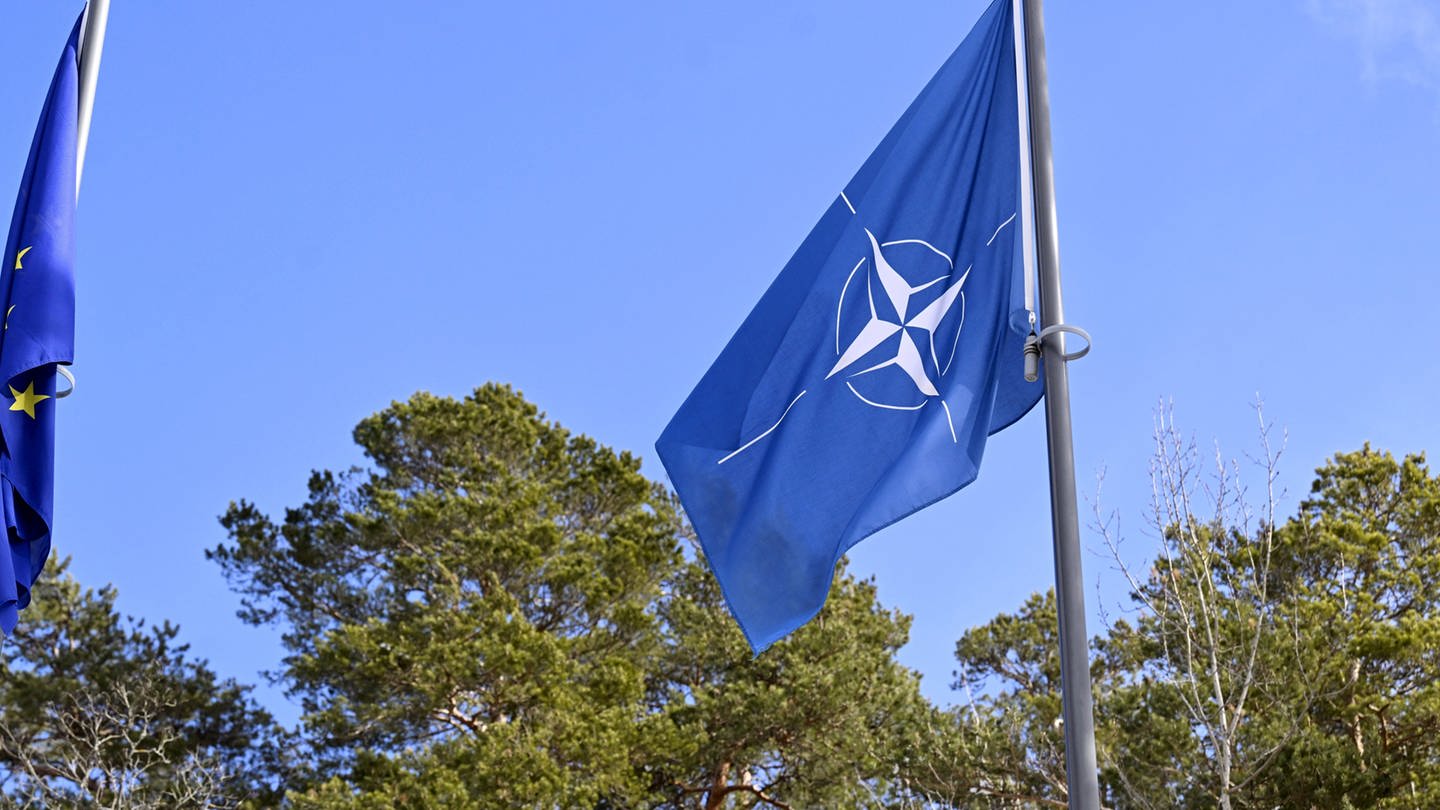 Eine Flagge mit dem weißen Nato-Symbol auf blauem Grund. (Foto: dpa Bildfunk, picture alliance/dpa/Lehtikuva | Vesa Moilanen)