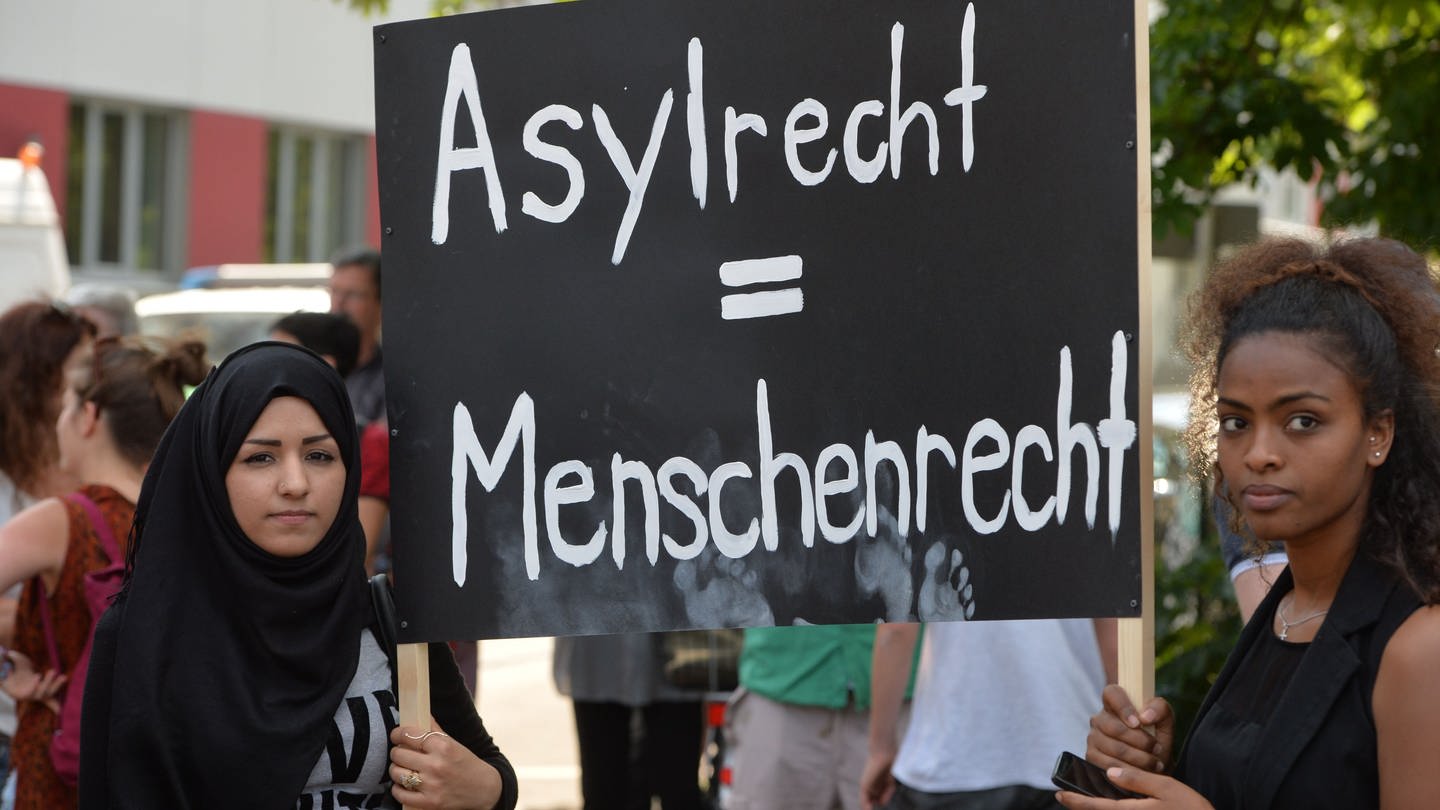 Teilnehmer einer Demonstration protestieren mit einem Schild mit der Aufschrift «Asylrecht = Menschenrecht (Foto: dpa Bildfunk, picture alliance / Timm Schamberger/dpa | Timm Schamberger)