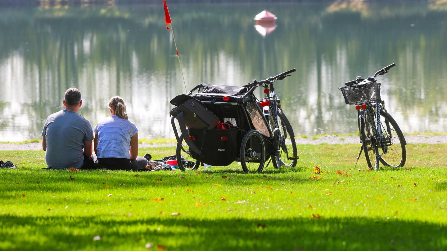 Ein Mann und eine Frau sitzen neben ihren Fahrrädern an einem See in der Sonne (Foto: dpa Bildfunk, picture alliance/dpa | Thomas Warnack)