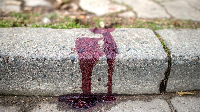 Nach einem Messerangriff auf eine Frau klebt Blut an einem Bordstein
