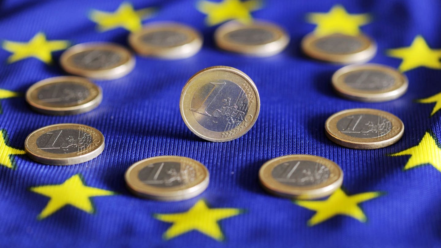 ILLUSTRATION - Auf einer Europafahne liegen Euro-Münzen. (Foto: dpa Bildfunk, picture alliance / dpa | Uli Deck)