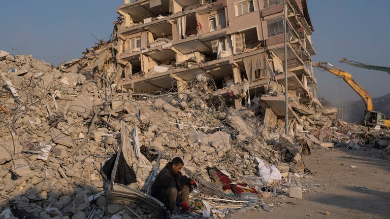 Ein Mann sitzt auf den Trümmern eines eingestürzten Gebäudes. (Foto: dpa Bildfunk, picture alliance/dpa/AP | Petros Giannakouris)