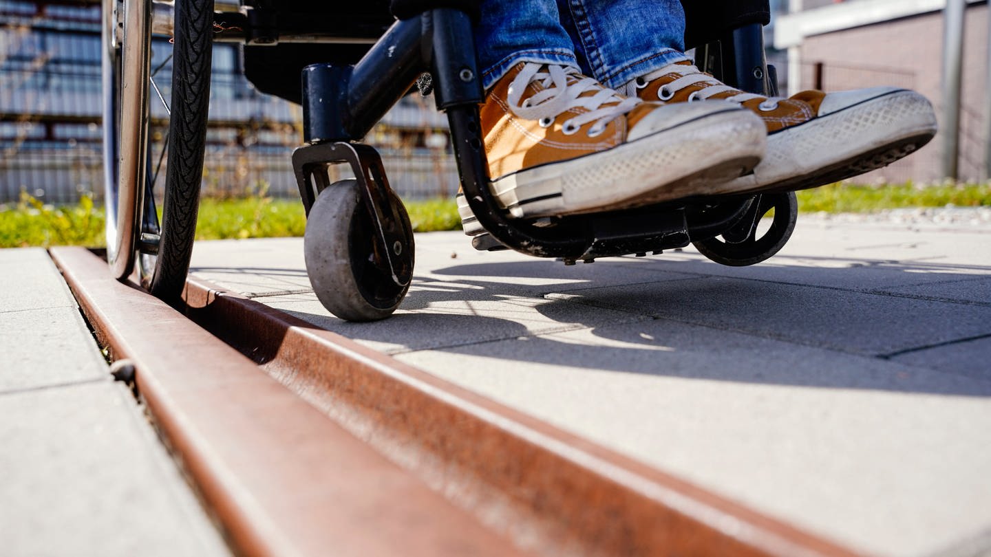 Eine Rollstuhlfahrerin bleibt mit einem Reifen in einer Metallritze im Boden hängen. (Foto: dpa Bildfunk, picture alliance/dpa | Uwe Anspach)