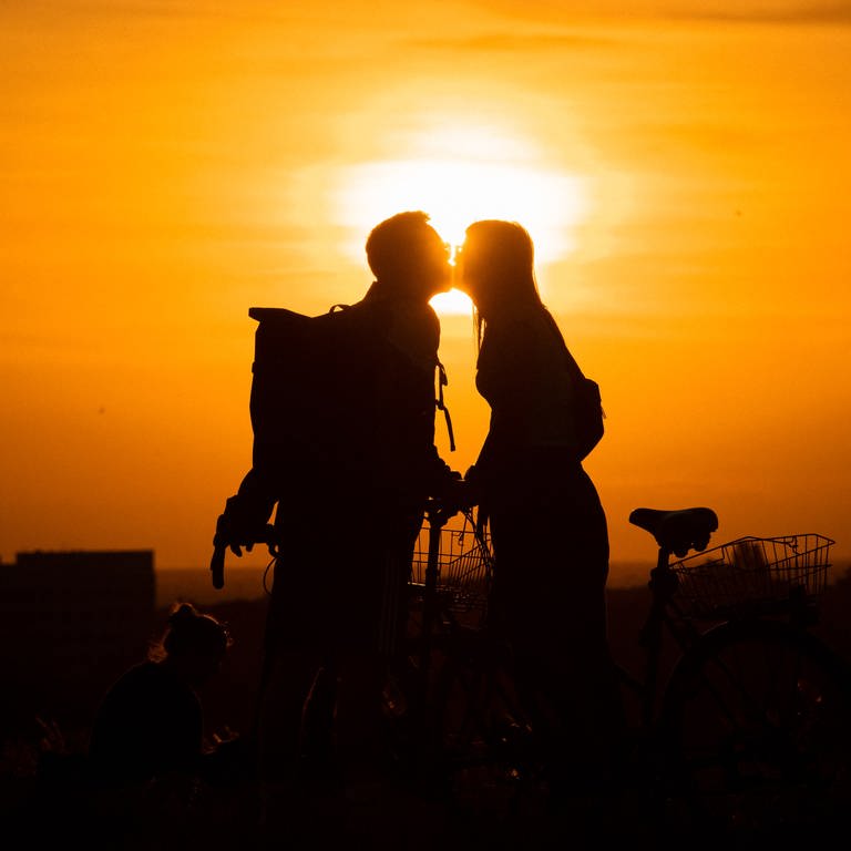 Im Licht der untergehenden Sonne küssen sich eine Frau und ein Mann auf dem Drachenberg. (Foto: dpa Bildfunk, picture alliance/ dpa/ Paul Zinken)