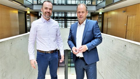 SWR-Korrespondent Oliver Neuroth und Joachim Stamp stehen in der Halle im ARD-Hauptstadtstudio nebeneinander und schauen in die Kamera (Foto: SWR, Foto: Nicole Gebauer)