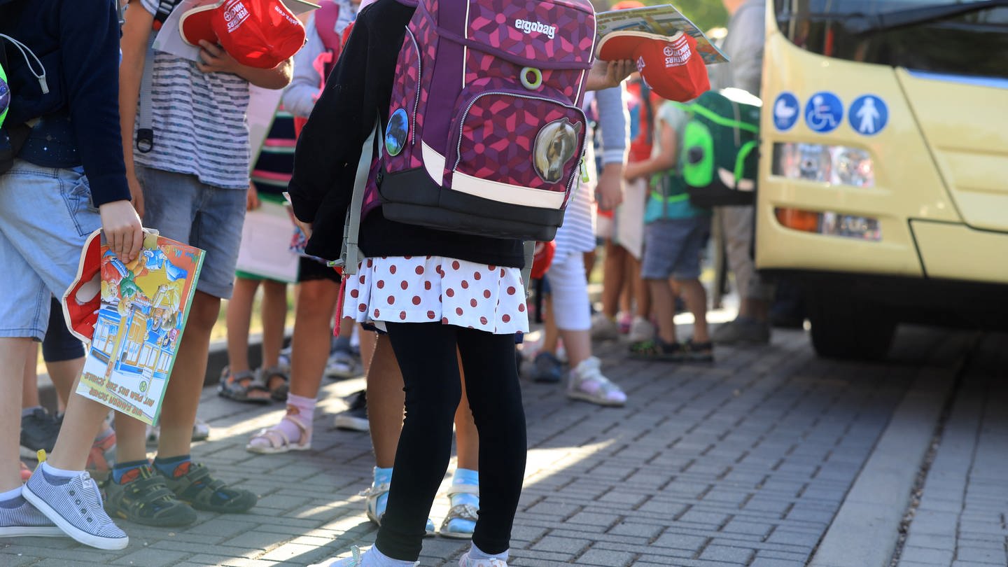 Kinder stehen mit ihrem Ranzen vor einem Schulbus. (Foto: dpa Bildfunk, picture alliance/dpa | Peter Gercke)