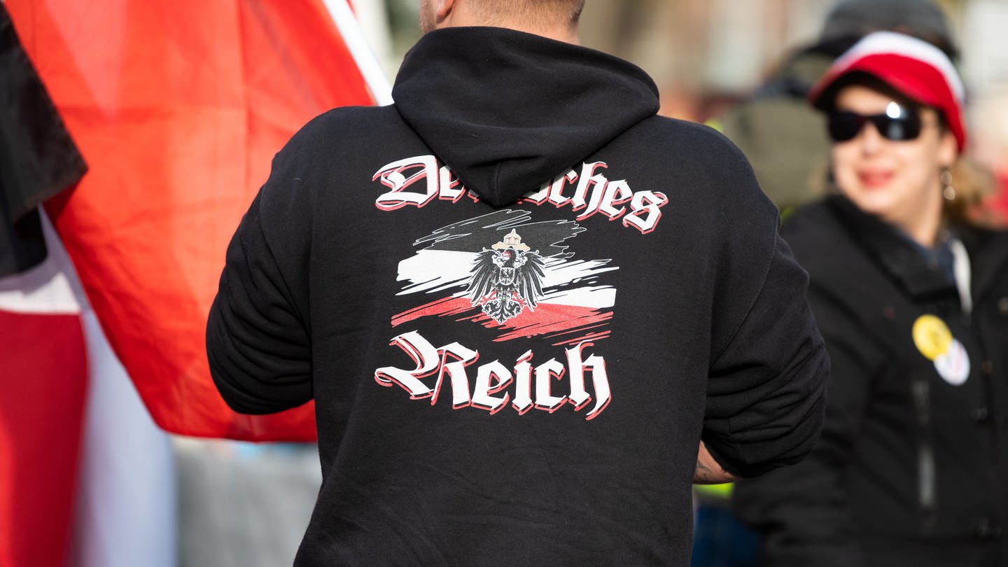 Ein Mann trägt einen Pullover mit dem Aufdruck «Deutsches Reich» bei einer Demonstration von Reichsbürgern. (Foto: dpa Bildfunk, picture alliance/dpa | Christophe Gateau)