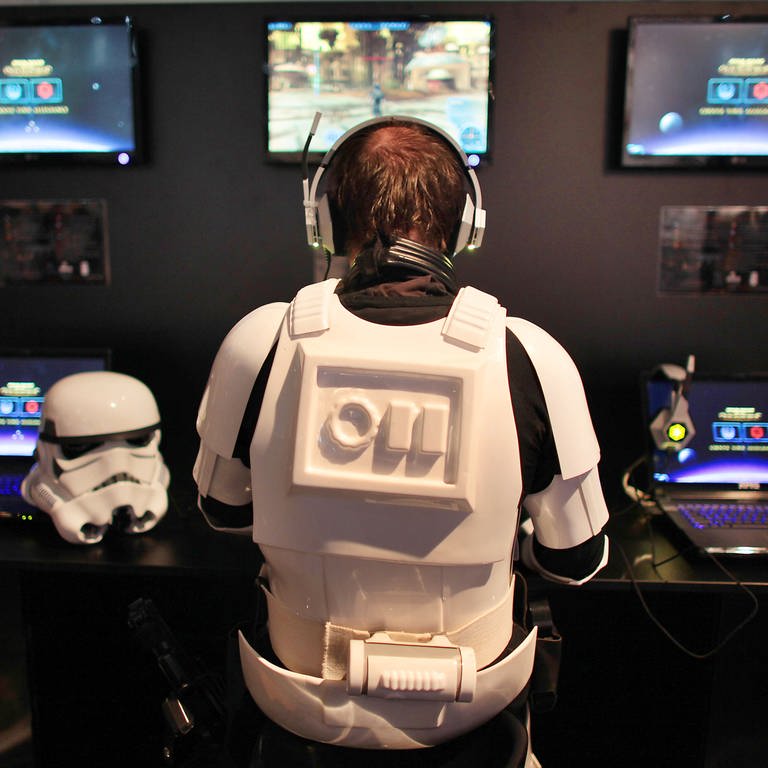 Ein als Star-Wars-Figur "Stormtrooper" verkleideter Mann probiert auf einer Messe ein Computerspiel aus.  (Foto: dpa Bildfunk, picture alliance / dpa | Oliver Berg)