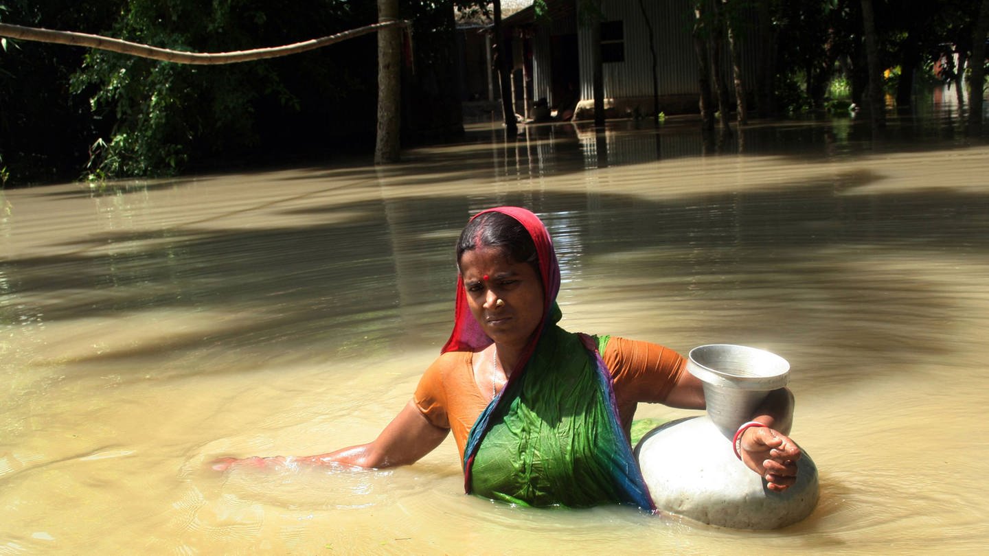 Frauen in der Klimakrise: Nach einer Flut in Bangladesch watet eine Frau durch brusthohes Wasser (Foto: IMAGO, IMAGO / UIG)