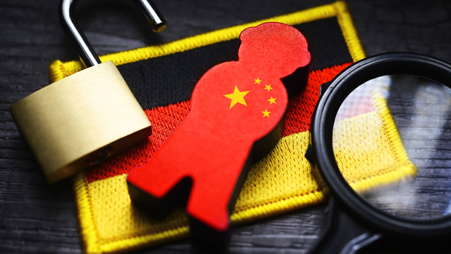 FOTOMONTAGE, Spion-Figur mit China-Fahne auf der Fahne von Deutschland, Symbolfoto chinesische Spionage (Foto: IMAGO, IMAGO / Christian Ohde)