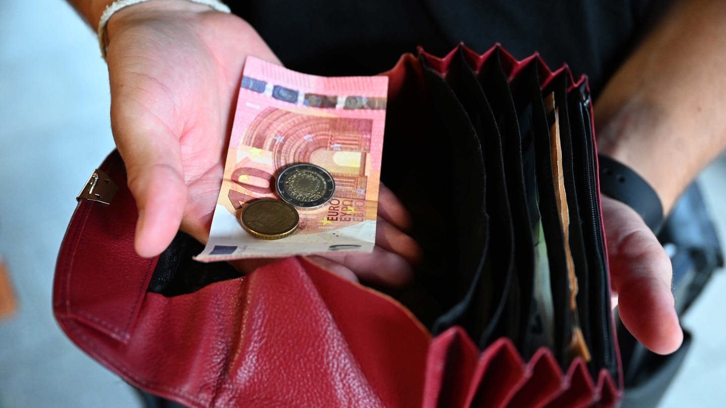 Ein Kellner eines Restaurants hält einen Geldbeutel in der Hand, während er in der anderen Hand Geld hält. (Foto: dpa Bildfunk, picture alliance/dpa | Felix Hörhager)