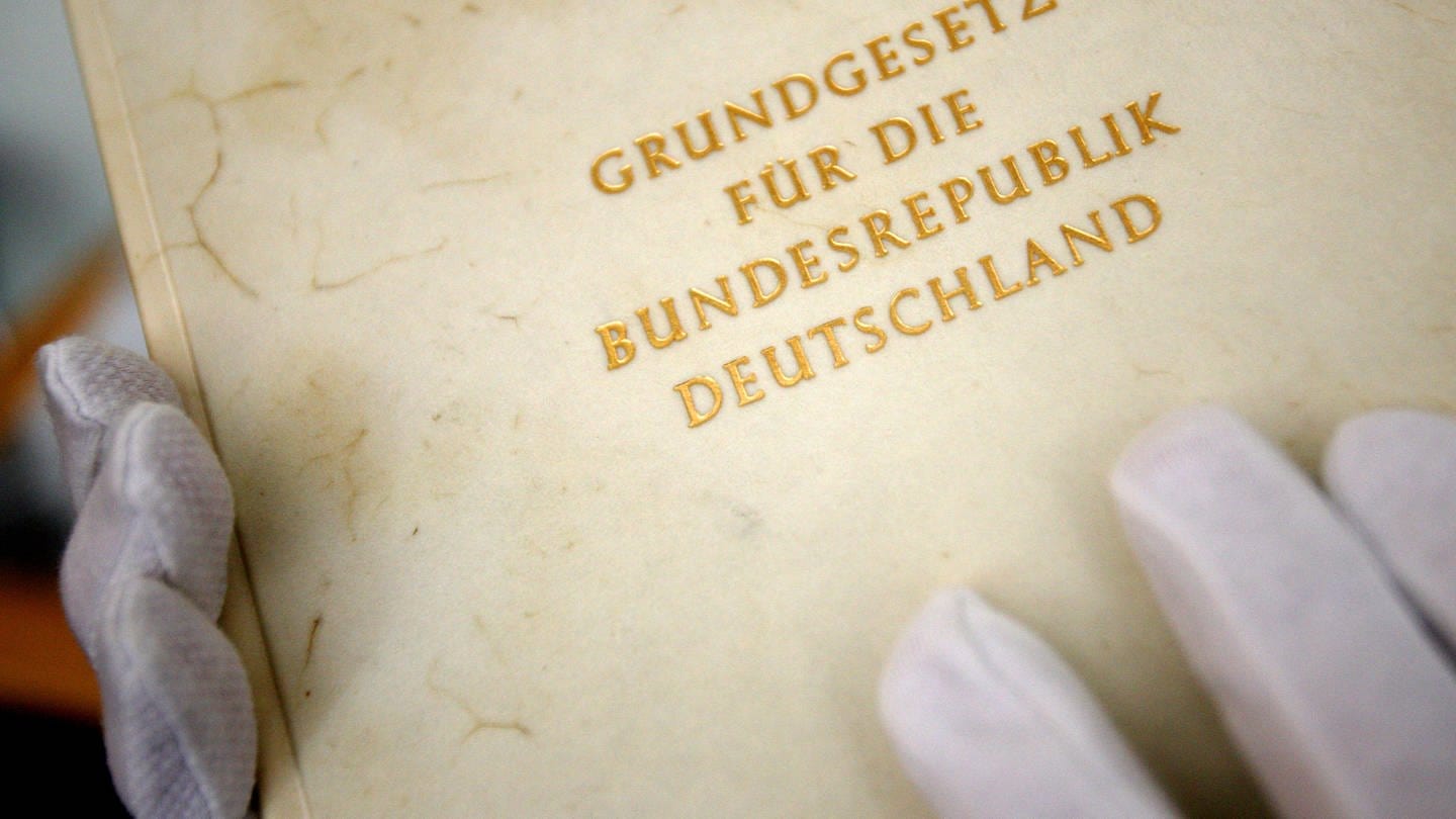 Ein Mitarbeiter zeigt im Haus der Geschichte in Bonn ein Faksimile des Grundgesetzes der Bundesrepublik Deutschland. (Foto: dpa Bildfunk, picture-alliance/ dpa | Oliver Berg)