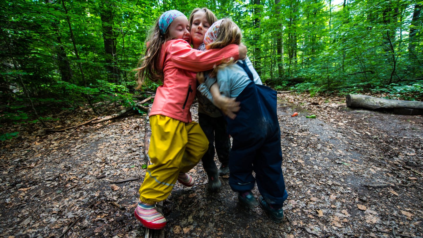 Drei Kinder stehen auf einem Waldweg und umarmen sich. (Foto: dpa Bildfunk, picture alliance/dpa | Andreas Arnold)