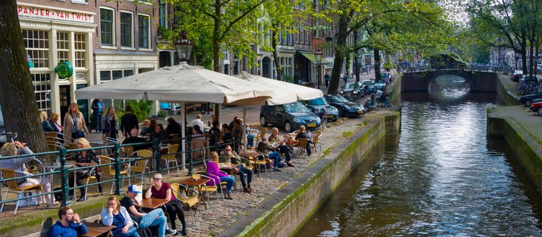 Die Niederlande schaffen viele ihrer Corona-Beschränkungen ab: Wer dort, wie hier in Amsterdam, etwa in ein Café oder Restaurant gehen möchte, muss zukünftig einen Corona-Gesundheitspass haben, um nachzuweisen, dass er oder sie geimpft, genesen oder getestet ist. (Foto: IMAGO, IMAGO / agefotostock)