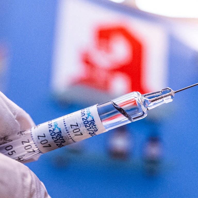Ein Apotheker hält eine Spritze mit Grippeschutzimpfstoff vor dem Logo der Apotheke. (Foto: dpa Bildfunk, picture alliance/dpa | David Inderlied)