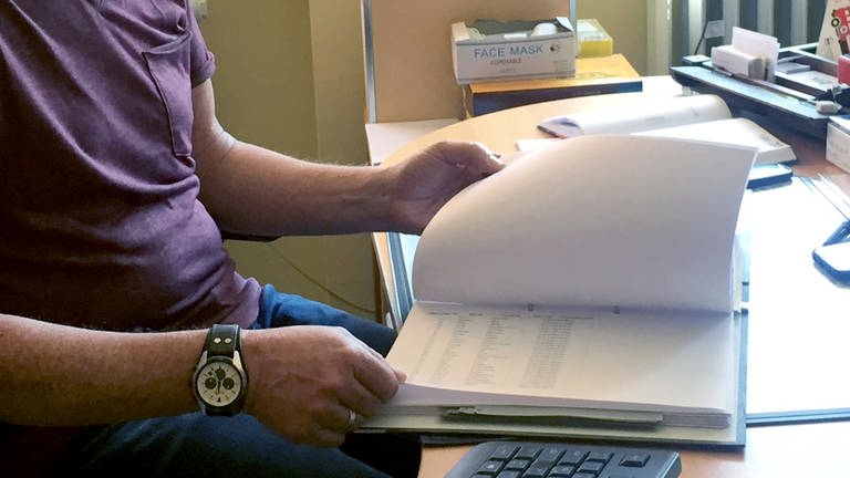 Ein Mitarbeiter in der Verwaltung sitzt an seinem Schreibtisch und blättert in Akten (Foto: dpa Bildfunk, picture alliance/dpa | Ira Schaible)