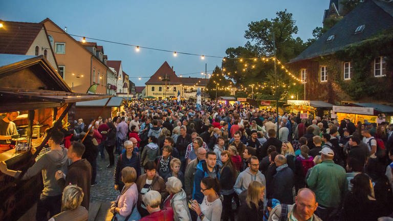 Viele Menschen tummeln sich auf einem Weinfest an den Ständen entlang. (Foto: IMAGO, IMAGO / Andreas Weihs)