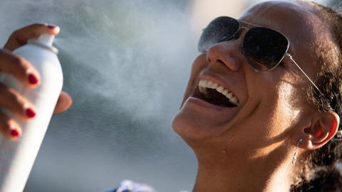 Eine Frau sprüht sich Wasser aus einer Sprühflasche ins Gesicht. (Foto: dpa Bildfunk, picture alliance/dpa/XinHua | -)