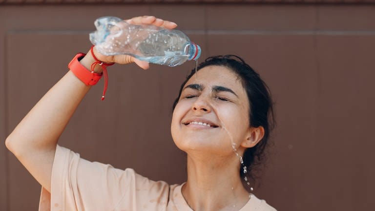 Eine Frau kühlt sich mit einer Flasche Wasser ab. (Foto: picture-alliance / Reportdienste, picture alliance / Zoonar | Max)