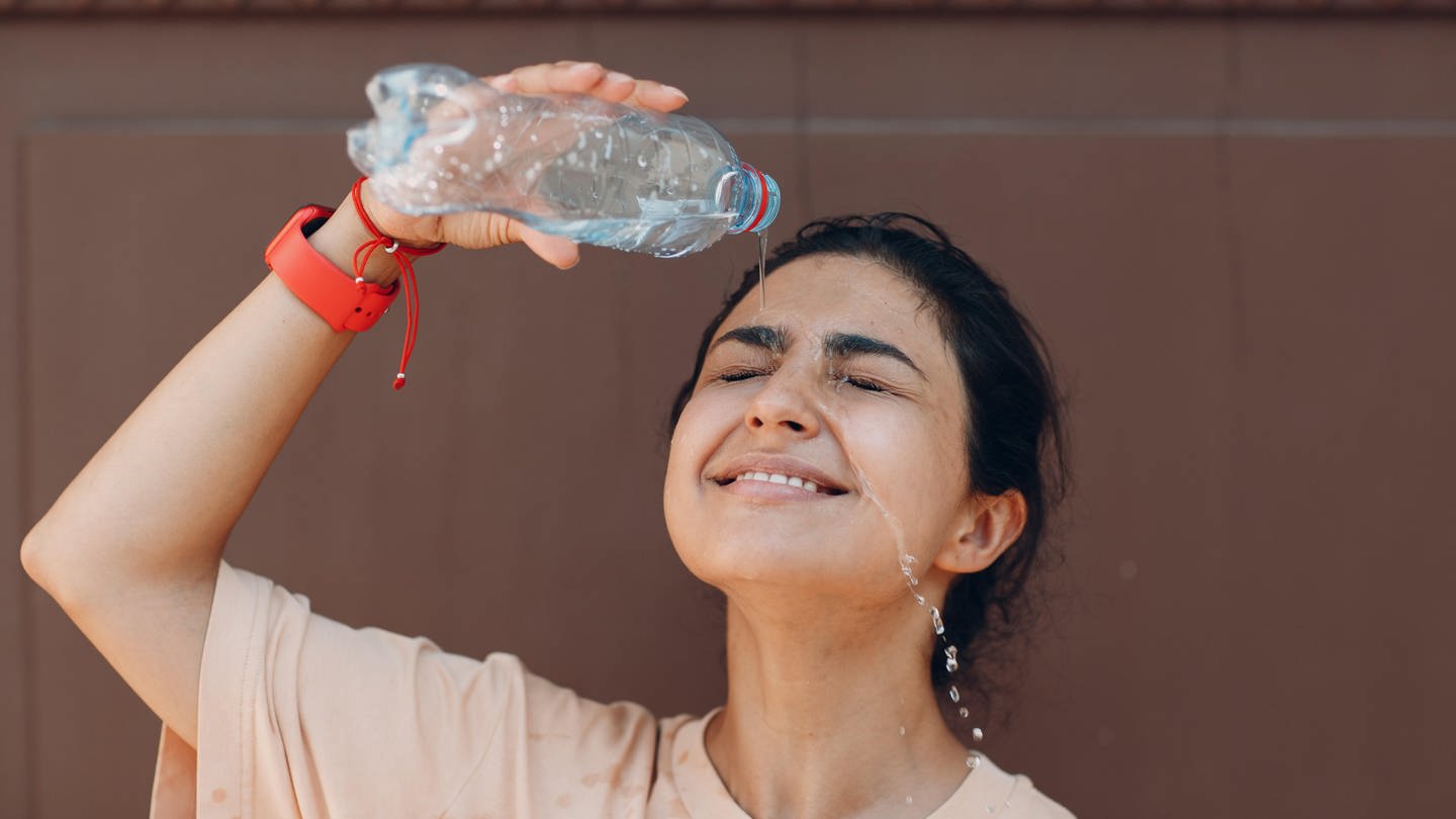 Eine Frau kühlt sich mit einer Flasche Wasser ab.