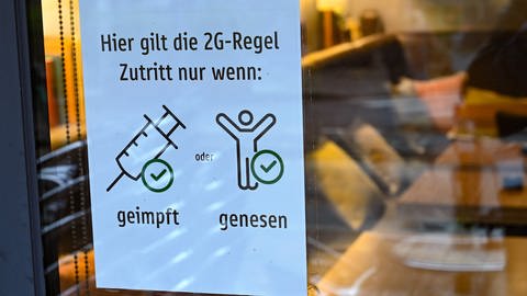 Am Fenster eines Cafés hängt ein Plakat mit der Aufschrift "Hier gilt die 2G-Regel". (Foto: picture-alliance / Reportdienste, picture alliance/dpa | Arne Dedert)