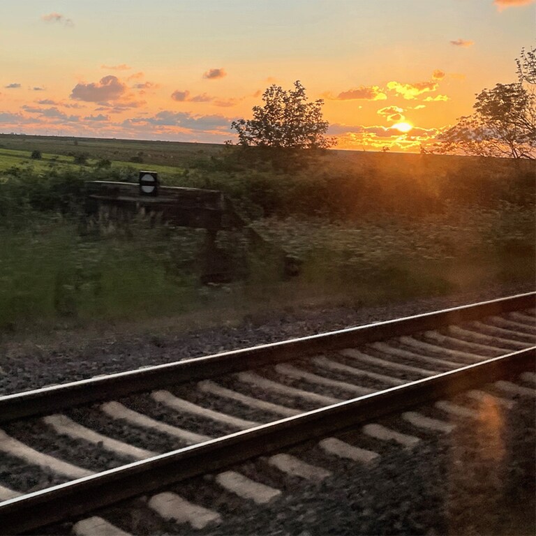 Hinter den Gleisen einer Zugstrecke geht die Sonne unter. (Foto: SWR, Carolin Keil)