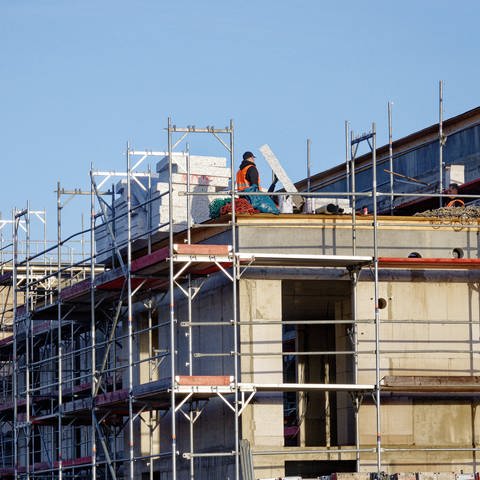 Eingerüstete, noch unfertige Neubauten stehen in einem Neubaugebiet. Die KfW-Förderung für energieeffiziente Häuser wird teilweise doch noch ausgezahlt.
