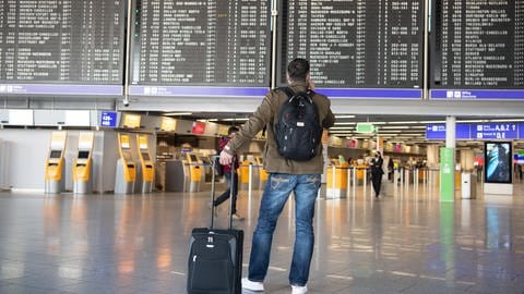 Ein Mann steht mit seinem Gepäck im nahezu menschenleeren Terminal 1 des Flughafens Frankfurt.