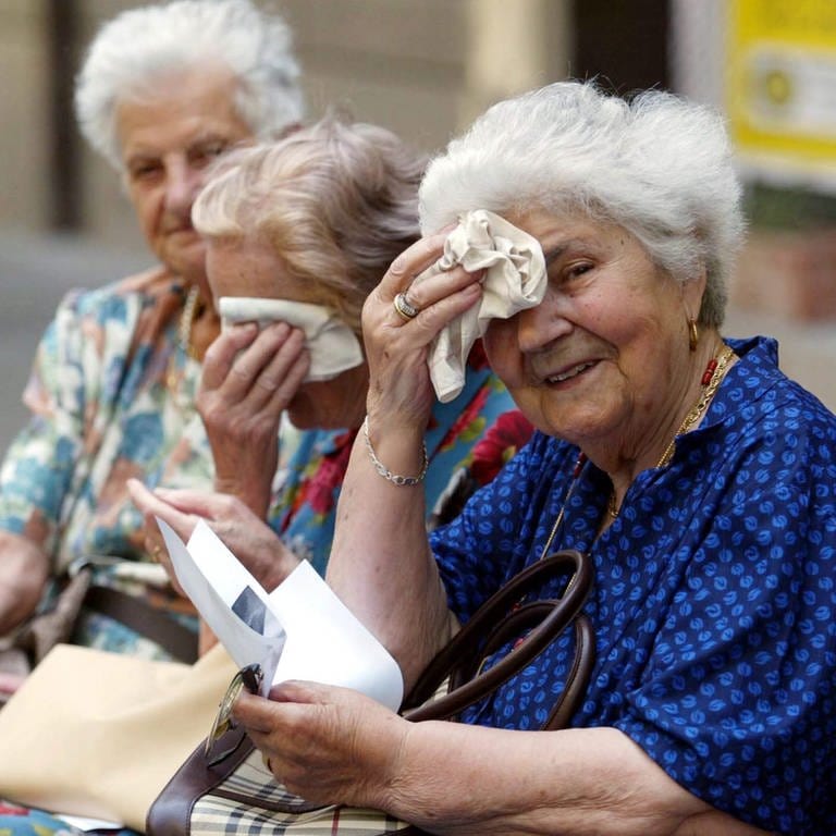 Drei alte Frauen wischen sich den Schweiß von der Stirn